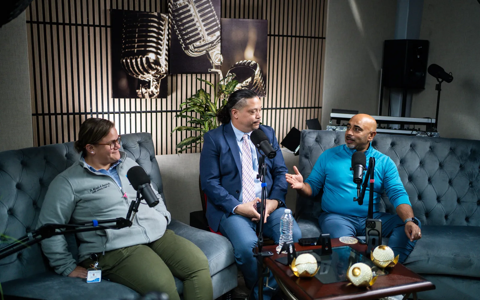 Dr. Michelle Benrimon, host Jose Rivera and John Johnson talking at microphones on a studio couch at I Axis Radio